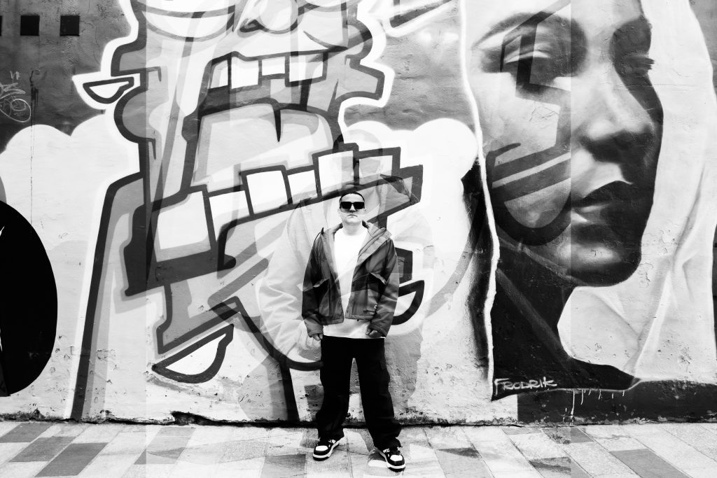 man with sunglasses standing in front of graffiti wall