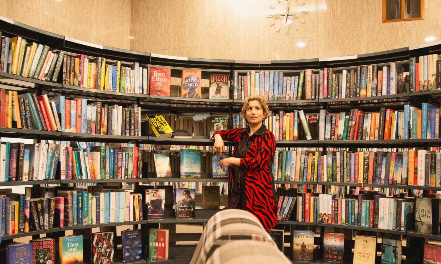 woman with blonde hair in front of a bookcase in a library